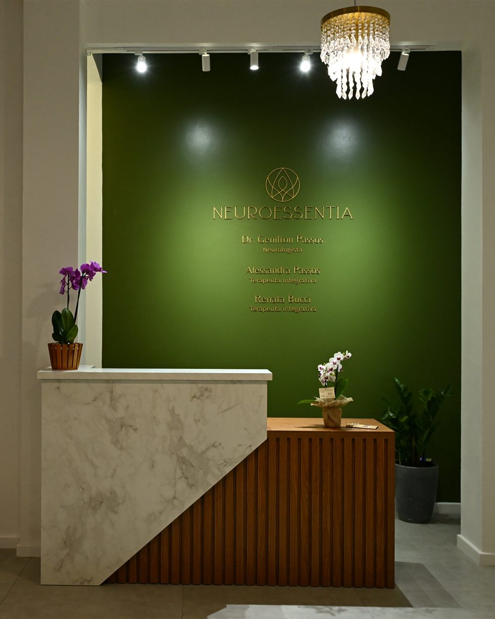 Recepção da Clínica Neuroessentia, com o logo em dourado sobre a parede verde
