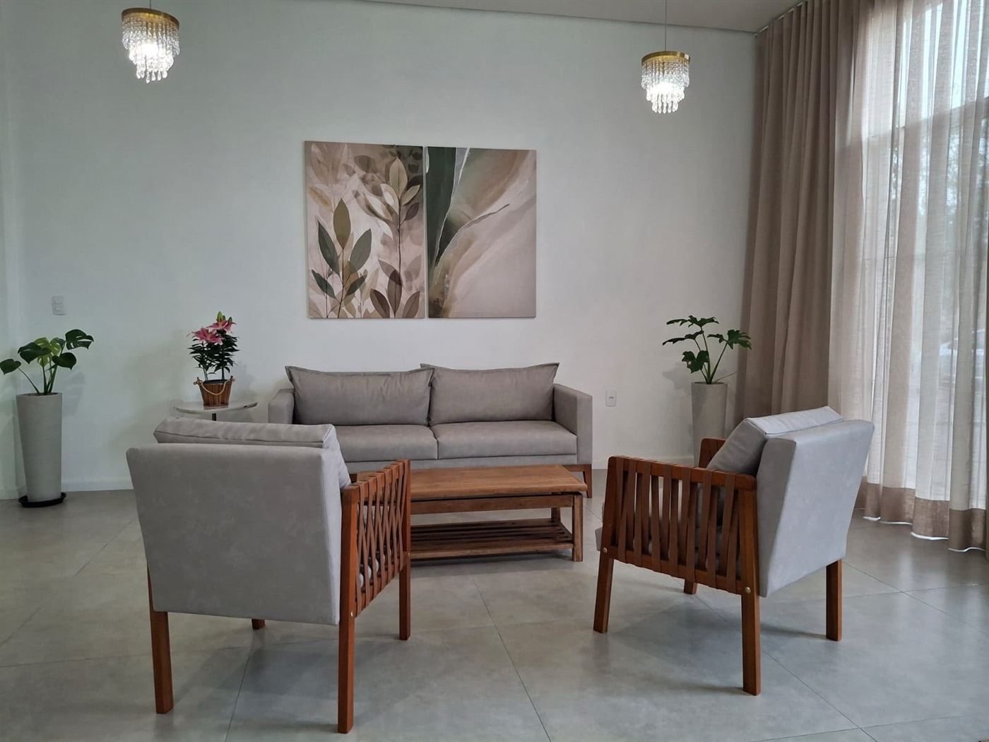 Sala de espera com sofá, poltronas de madeira e quadros de folhas